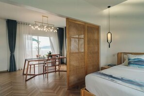 A hotel room with a bed, a dining table with chairs, a hanging light fixture, and a view through a window. - Puerto Galera Seaview Resort (Puerto Galera)