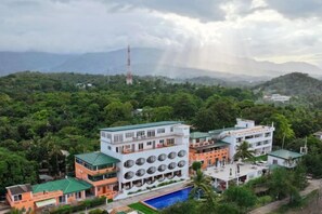 A multi-story building with a swimming pool, surrounded by lush greenery and mountains. - Puerto Galera Seaview Resort (Puerto Galera)