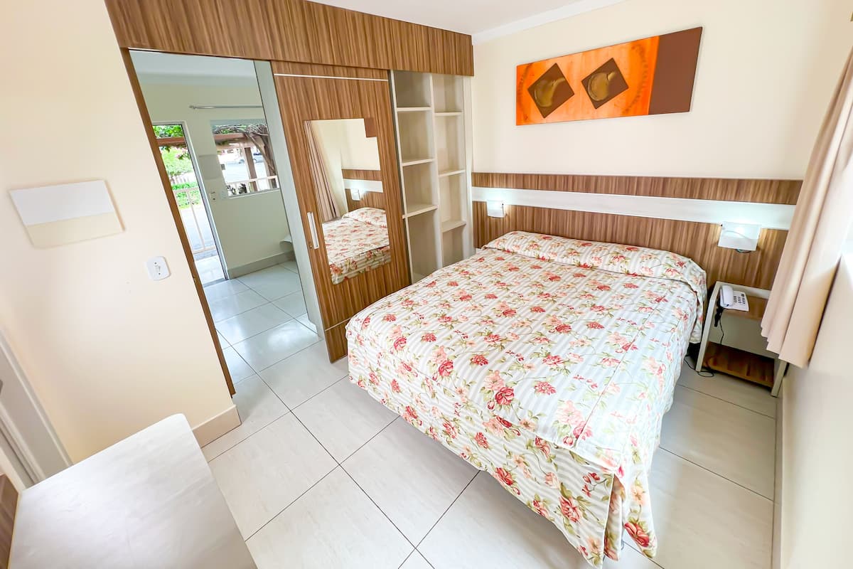 Un dormitorio con cama, armario, espejo y teléfono.