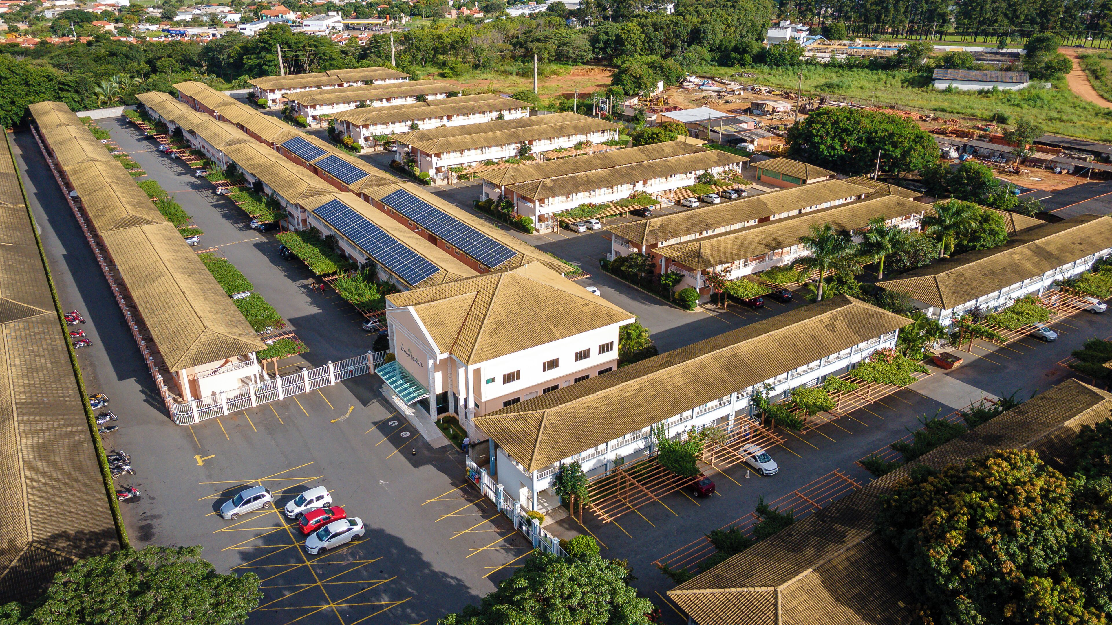 An aerial view of a hotel with multiple buildings, a parking lot, and solar panels on the roofs.
