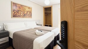 A hotel room with a bed, a nightstand, a painting, a wardrobe, and a door with a keypad lock. - Berceo Rooms Self Check-in (Logroño)