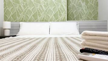 Una habitación de hotel con cama, almohadas, un control remoto y una pared con diseño.