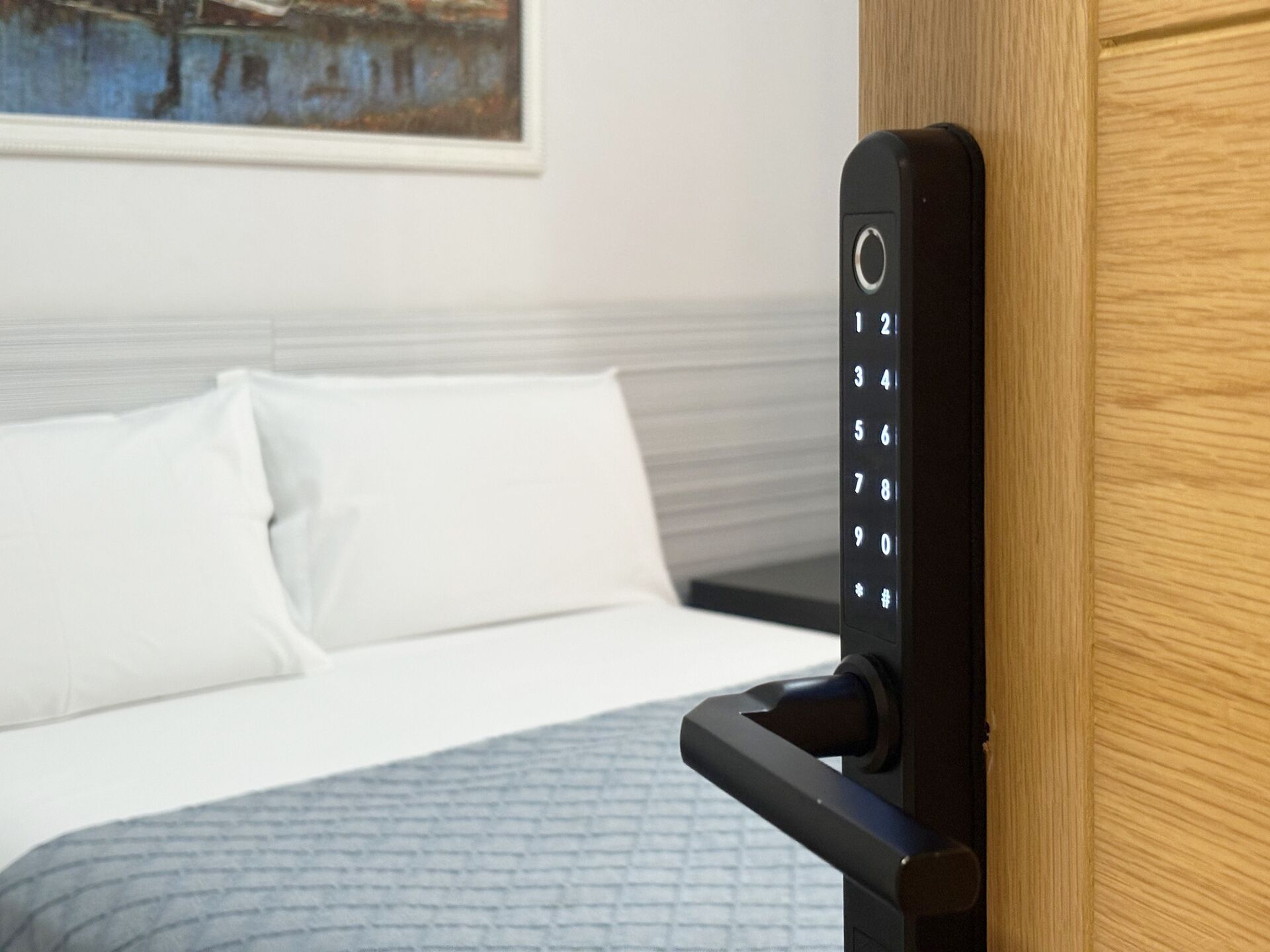 Une chambre d’hôtel avec un lit, un oreiller blanc et une porte dotée d’un système de verrouillage à clavier numérique.