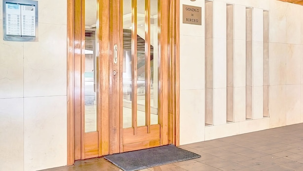 A hotel entrance with a wooden door, a sign reading "Gonzalo de Berceo", and a tiled floor. - Berceo Rooms Self Check-in (Logroño)