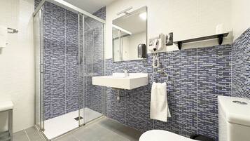 Un baño moderno con ducha de vidrio, lavamanos blanco y retrete.