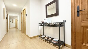A hallway with wooden doors, a console table with magazines, a wall-mounted mirror, and recessed ceiling lights. - Berceo Rooms Self Check-in (Logroño)