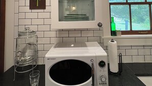 Een keuken met een magnetron, een glazen kast met servies, een waterdispenser en een raam met uitzicht.