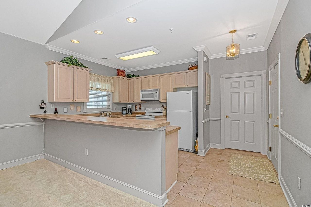 Kitchen with light wood cabinetry, breakfast bar, and tile flooring.