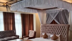 A bedroom with a large bed, a chaise lounge, a small table, and a bench. - Equator Pastoral Resort (Gambogi)