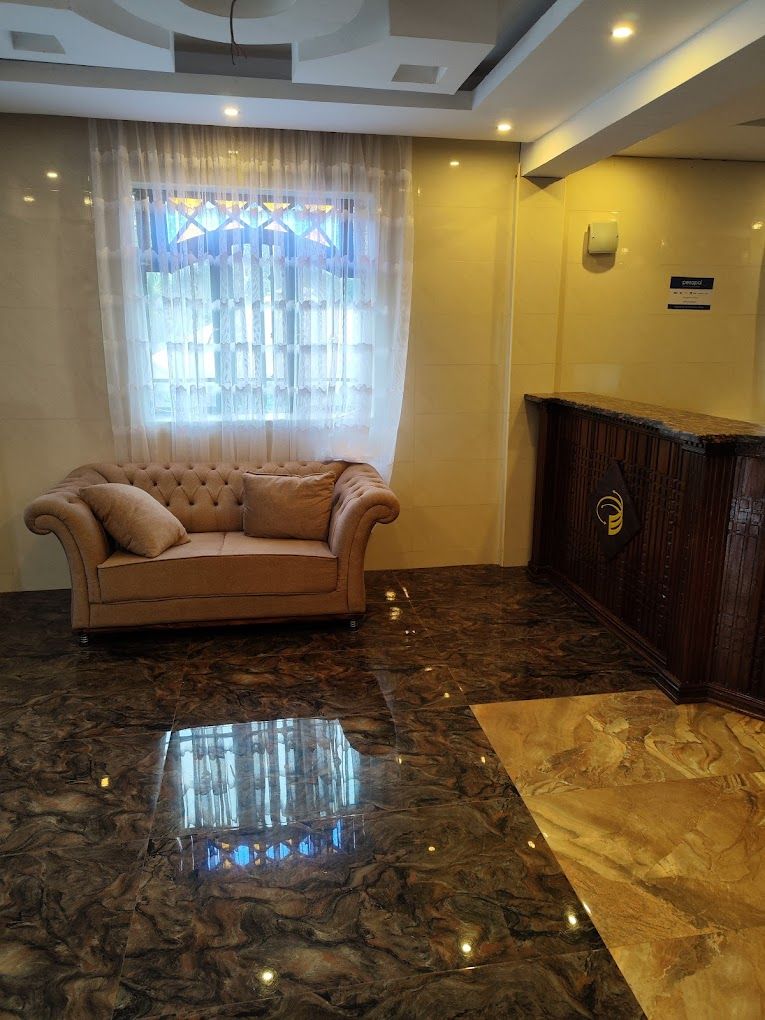 A lobby with a tufted sofa, a wooden reception desk, and a marble floor.
