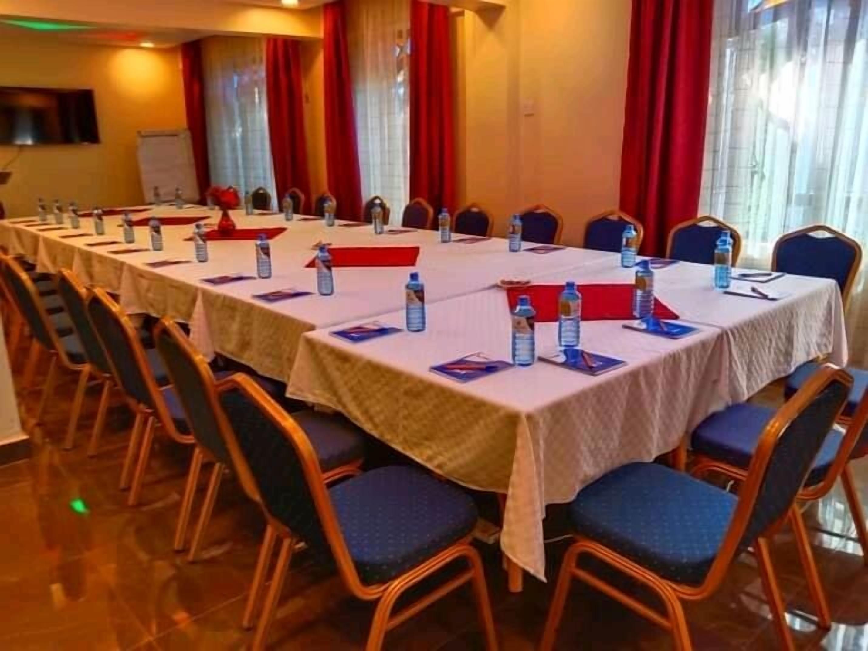 Un salón de conferencias con varias mesas y sillas, botellas de agua y tarjetas de identificación en cada mesa.
