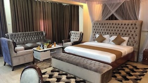 A hotel room with a large bed, two armchairs, a small table, and a sofa. - Equator Pastoral Resort (Gambogi)
