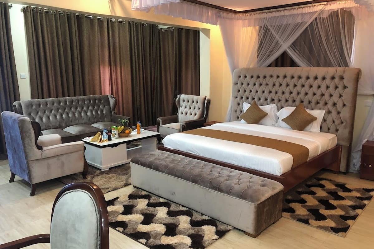 A hotel room with a large bed, two armchairs, a small table, and a sofa.