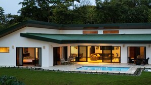 A modern house with a swimming pool, large glass doors, and a green roof.