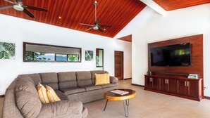A living room with a sofa, a coffee table, a TV, and a ceiling fan.