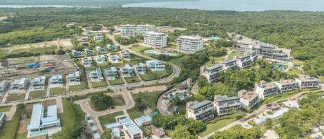 An aerial view of a resort with multiple buildings, roads, and a large pool area.