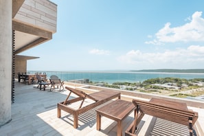 A terrace with wooden furniture and a view of the sea.