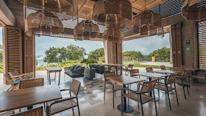 An outdoor dining area with wicker furniture and hanging lights. - Oceanview 3BR Condo w spa gym (Cartagena)