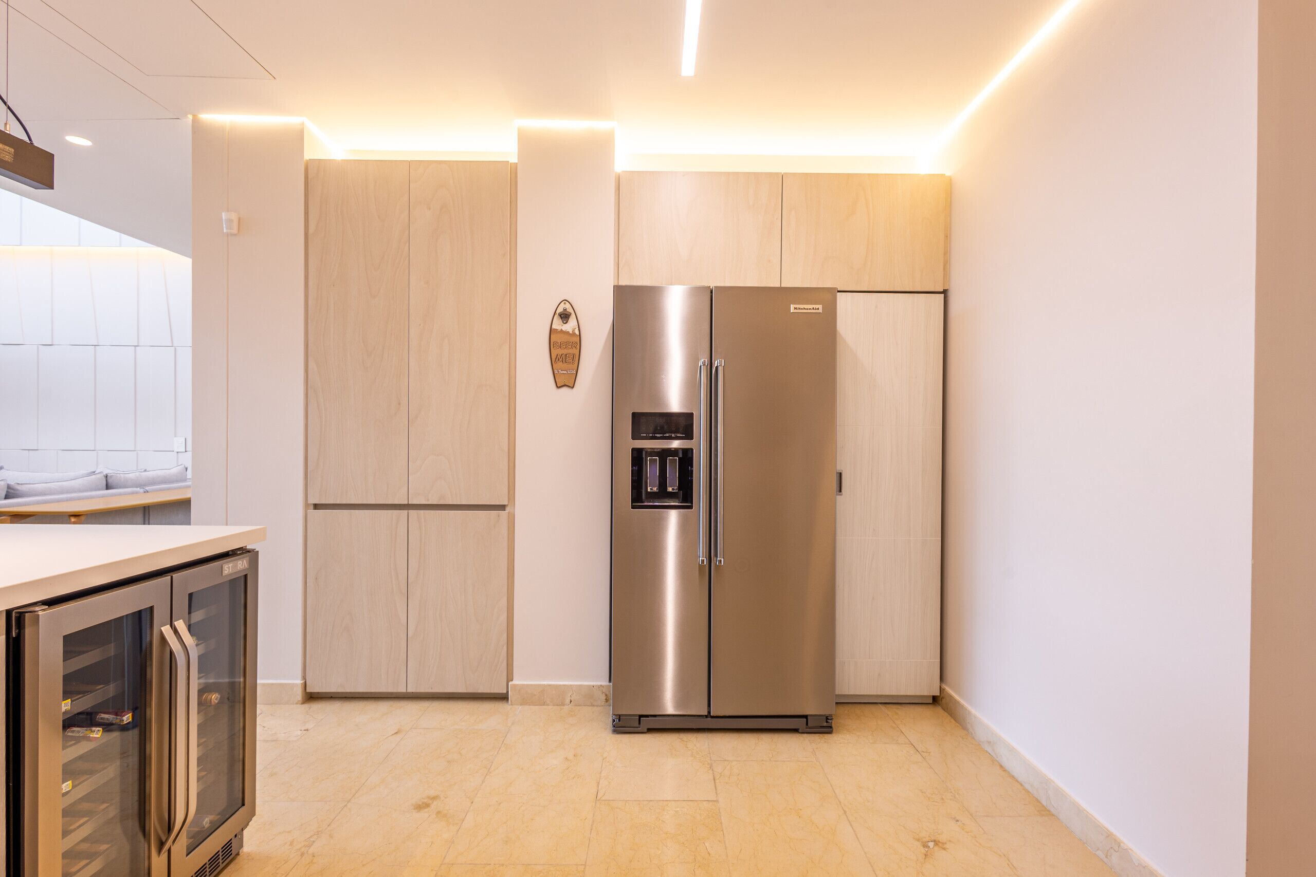 A modern kitchen with a stainless steel refrigerator, wooden cabinets, and a built-in oven.