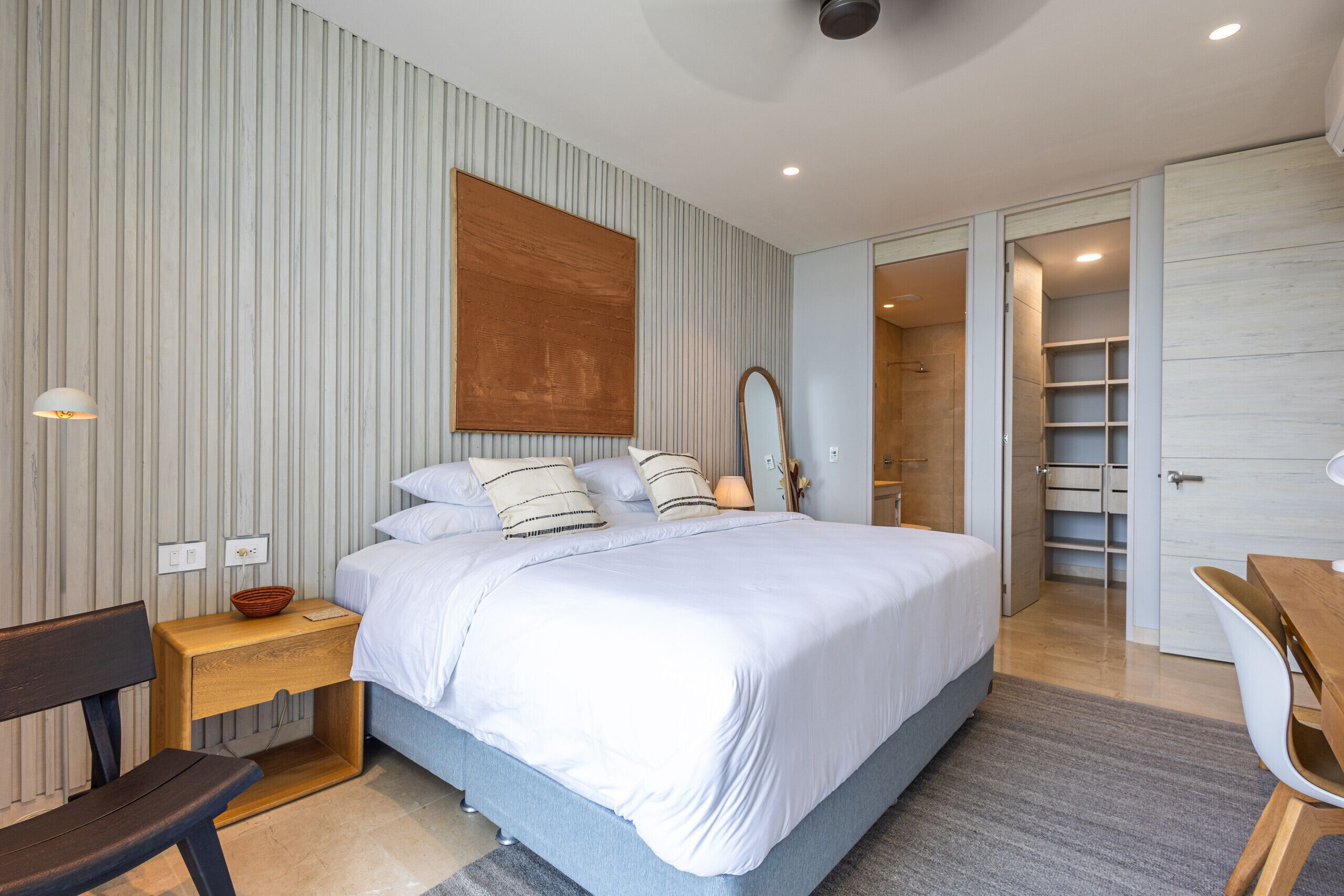 Una camera da letto moderna con un letto grande, comodini, una panca in legno e un armadio.