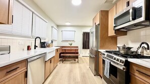 Una cocina moderna con armarios de madera, un refrigerador de acero inoxidable, horno empotrado y microondas.