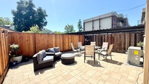 Un patio con mobiliario exterior, cerca de madera y calentador de agua.