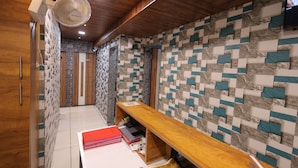 Un couloir avec un plafond en bois, un mur orné d’un motif géométrique, un banc en bois et une porte portant le numéro 407.