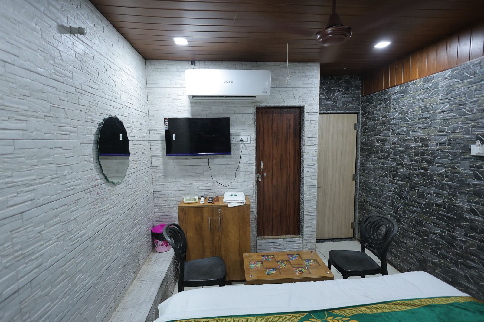 A small, compact room with a bed, a desk, a chair, a television, and a wardrobe.