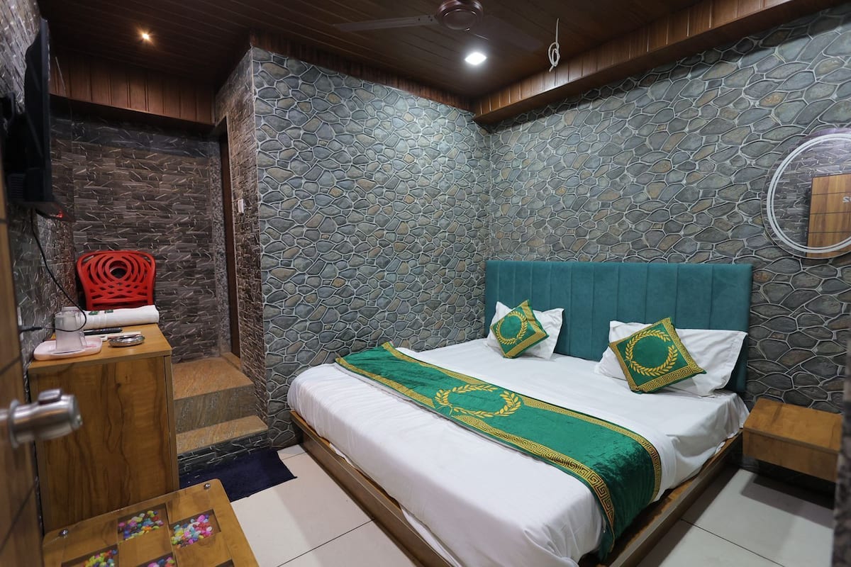 A bedroom with a stone-patterned wall, a bed with green and white bedding, and a wooden nightstand.