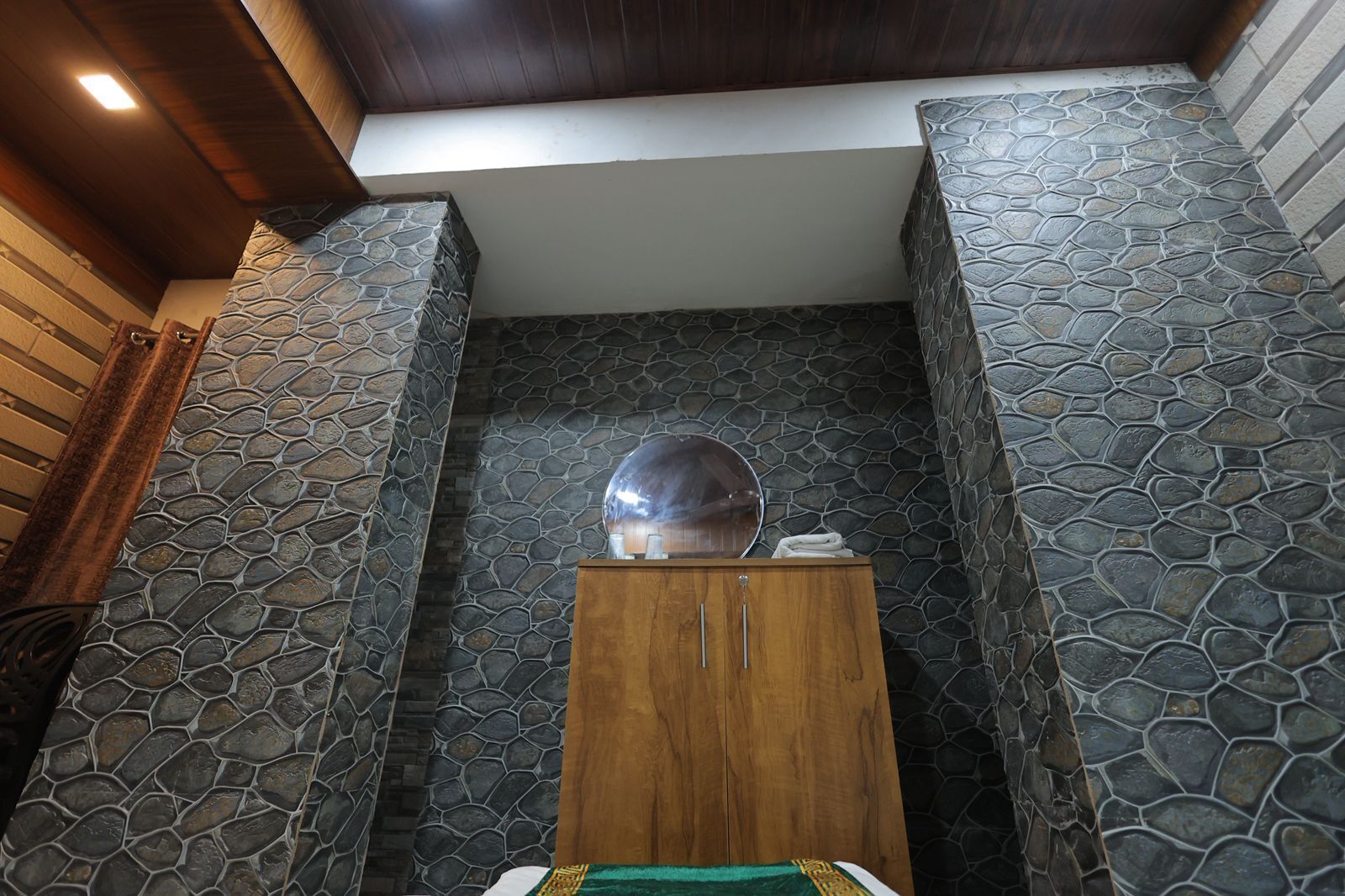 Un baño con paredes de piedra, un armario de madera y un espejo.