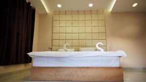 A modern hotel room with a large bed, a headboard with a quilted design, and a wooden platform. - The Great Golden Pyramid (Giza)