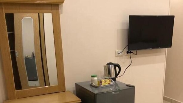 A compact room with a wooden cabinet, a small refrigerator, and a flat-screen TV mounted on the wall. - The Great Golden Pyramid (Giza)