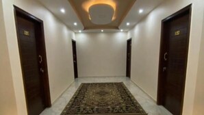 A hallway with a marble floor, a patterned rug, and two dark wooden doors with numbers on them. - The Great Golden Pyramid (Giza)