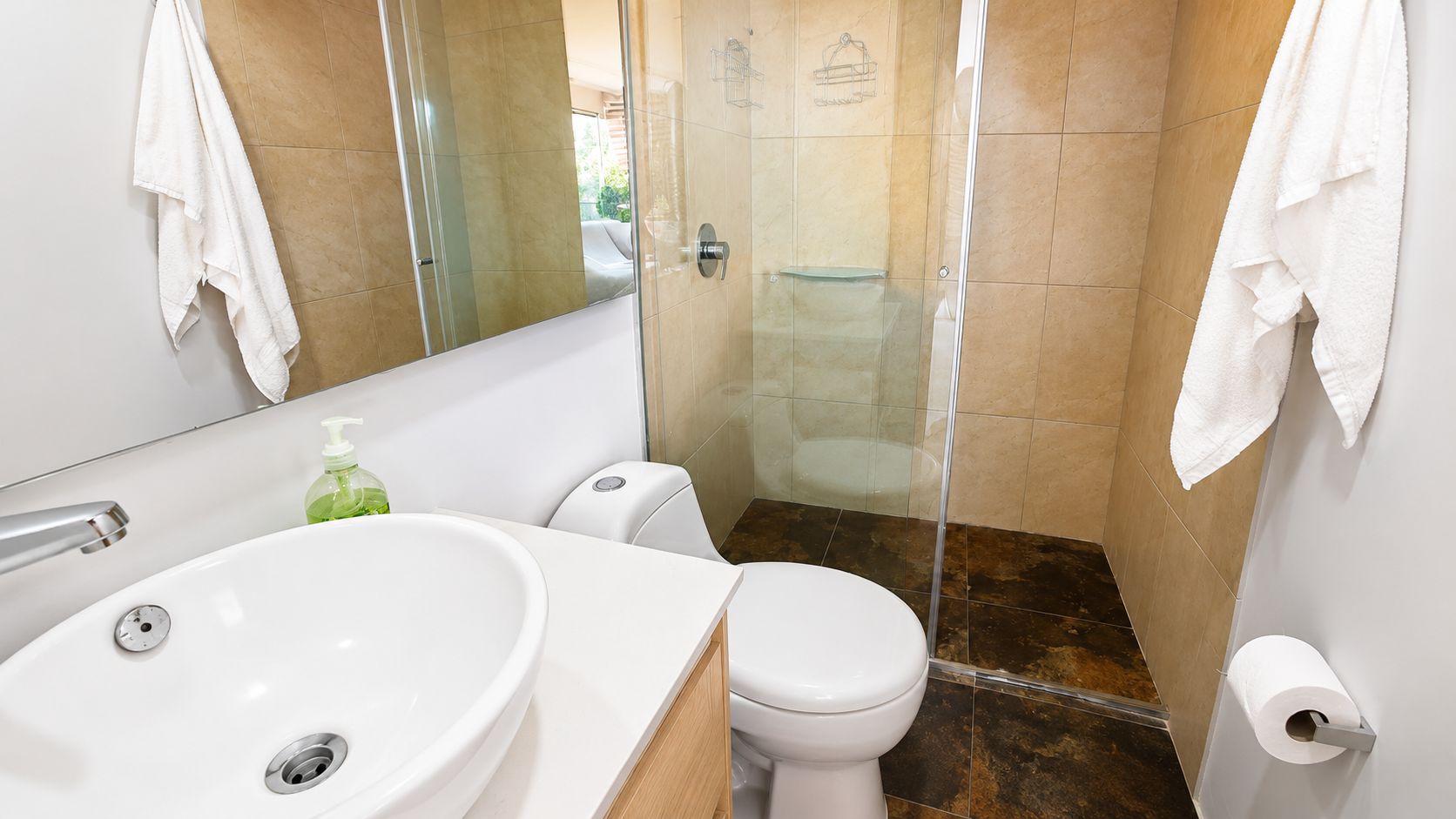 A bathroom with a white sink, toilet, and shower stall.