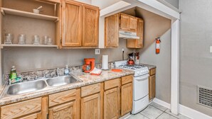 A kitchen with wooden cabinets, a double sink, a stove, and a coffee maker. - Urban Comfort Nook - Walk to Overton Park (Memphis)