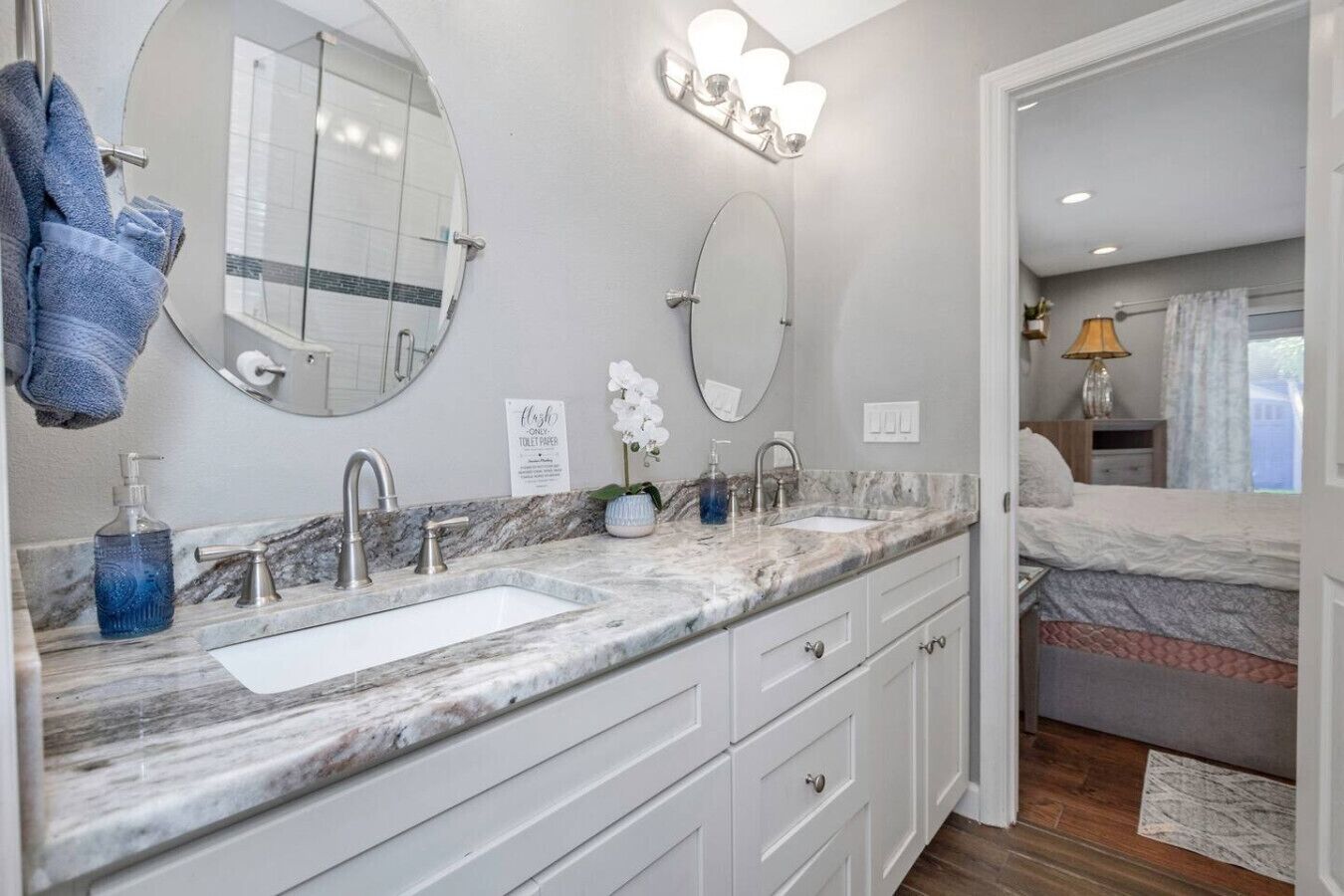 A modern bathroom with two sinks, marble countertops, and a large mirror.