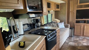 A compact kitchen with a stove, sink, and countertop appliances.