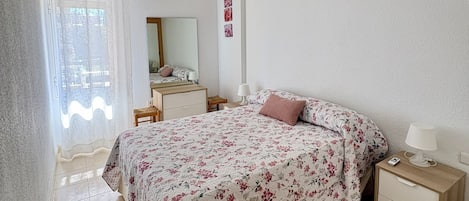 Un dormitorio con cama, mesita de noche y ventilador de techo.