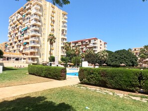 Un edificio residencial de varios pisos con balcones, piscina y césped bien cuidado.