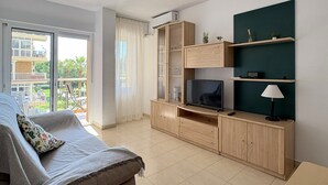 Uma sala de estar moderna com sofá, móvel para TV e vista para uma varanda.