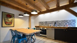 A kitchen with a wooden table and blue chairs, a tiled backsplash, and modern appliances. - The Munster valley stable (Breitenbach-Haut-Rhin)