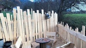 A wooden deck with a round table and benches, surrounded by a wooden fence. - The Munster valley stable (Breitenbach-Haut-Rhin)