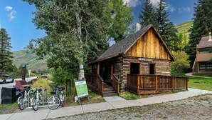 A rustic cabin with a wooden exterior, a porch, and a sign indicating it is part of the Pikkin Creek area. - Mountain Retreat in East Vail, 2BR/2BA Condo w/ Pool & Hot Tub (Vail)