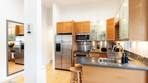 A modern kitchen with stainless steel appliances, wooden cabinets, and a bar stool. - Mountain Retreat in East Vail, 2BR/2BA Condo w/ Pool & Hot Tub (Vail)
