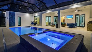 A swimming pool with a glass bottom and a covered patio area. - Golden Acres Sports Ranch – Luxe Retreat with Pickleball, Pool & Games (Naples)