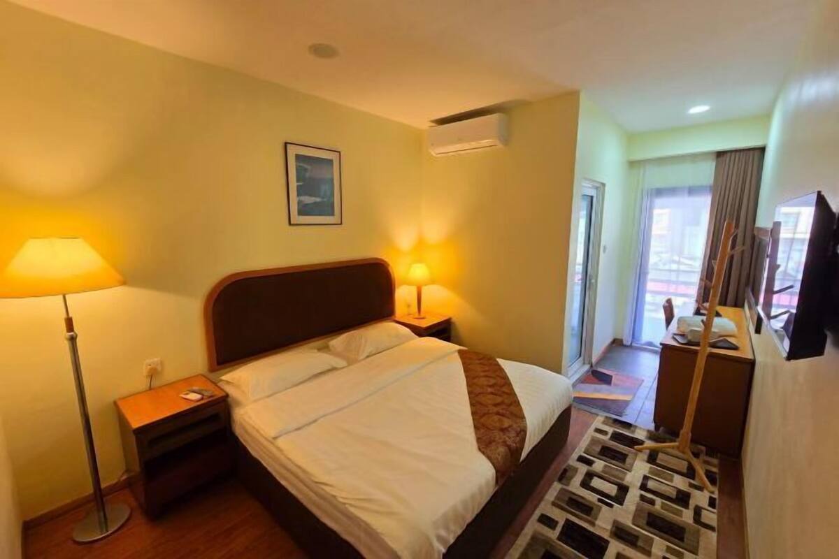 Une chambre d’hôtel avec un lit, deux lampes de chevet, une petite table et un téléviseur.
