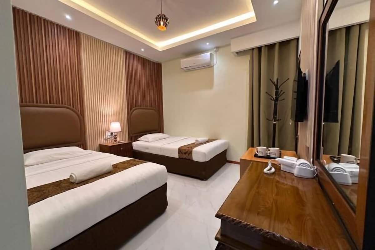 Une chambre d’hôtel avec deux lits, un bureau en bois, un miroir et une télévision.