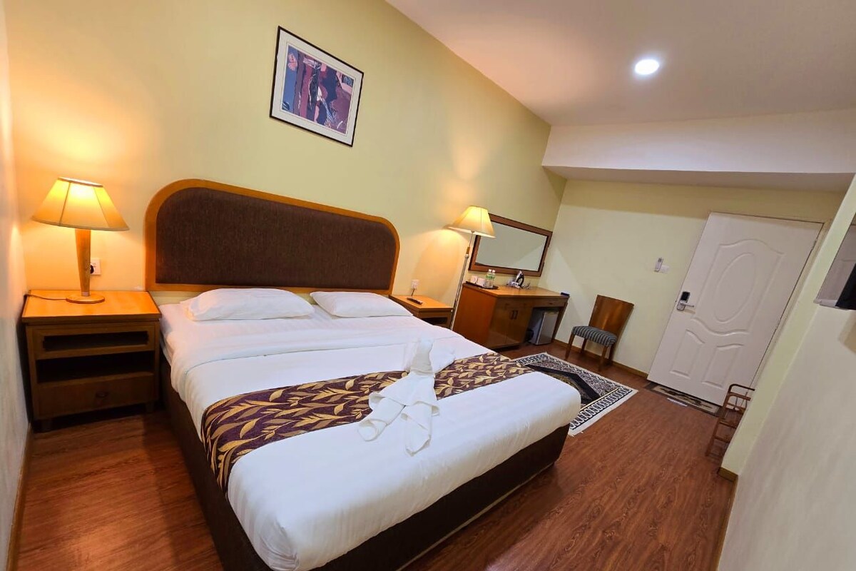 Une chambre d’hôtel comprenant un lit, deux tables de chevet, un bureau, une chaise, une porte et un miroir.