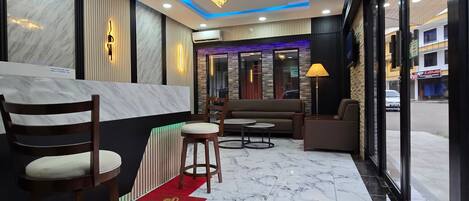 A hotel lobby with marble flooring, seating areas, and a modern chandelier.