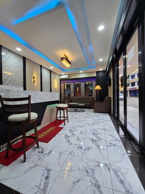 A hotel lobby with marble flooring, seating areas, and a modern chandelier.